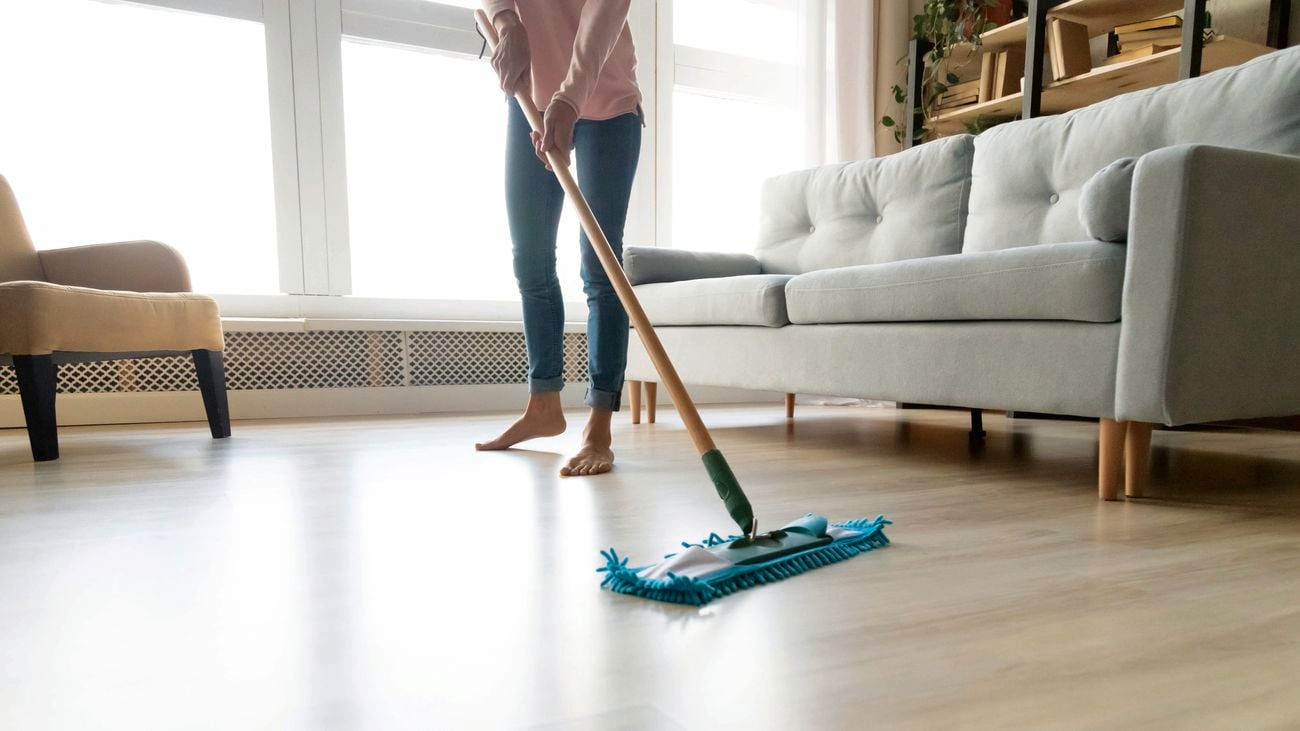 Person using mop to clean hardwood floors.