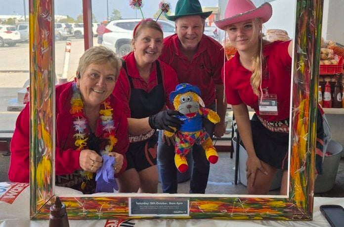 A Bunnings Team Member adding a pin to a boy with a Bunnings apron on it.