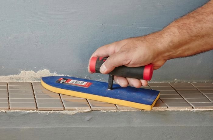 A rubber trowel used to press mosaic tiles into pre applied tile adhesive
