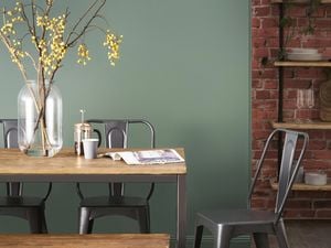 A painted green wall behind a dining table.