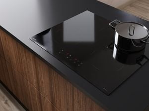 Black stove top with pot, on a black benchtop with dark brown wood-look drawers