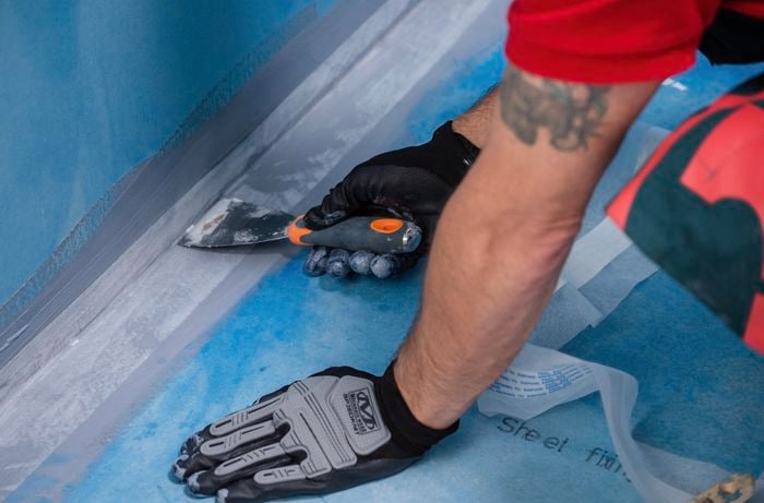 Man securing edges with reinforcing fabric. 