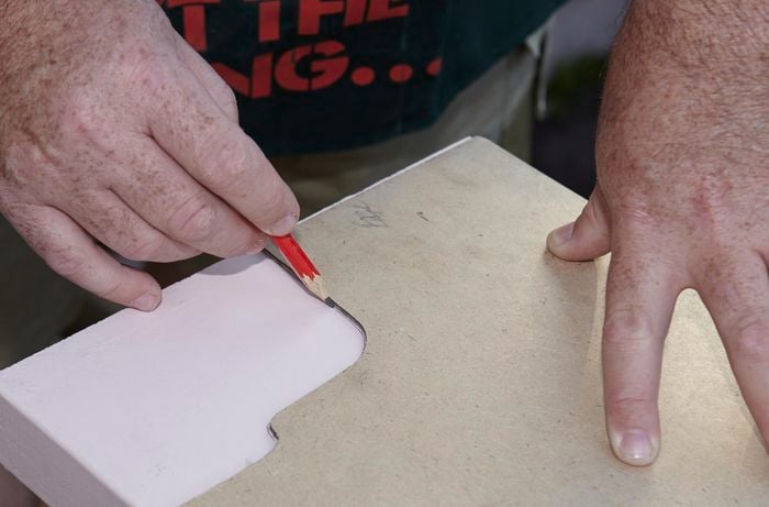 Person using cardboard to trace shape needed for pergola frame.