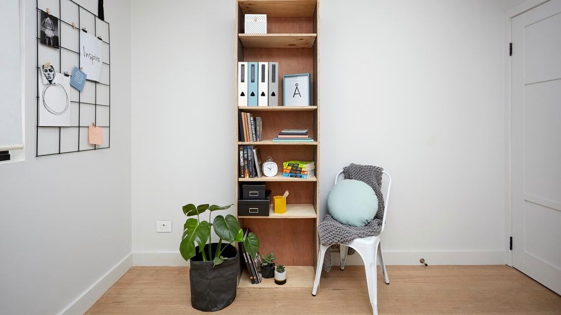 A narrow timber shelving unit next to a potted plant and chair