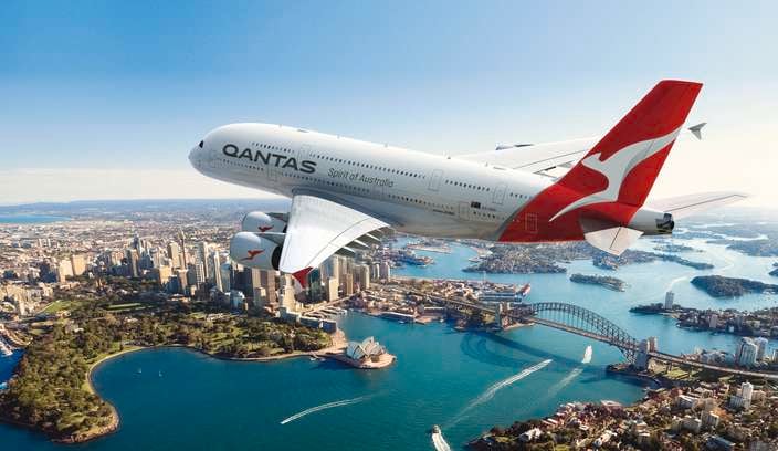 A Qantas plane in the sky amongst clouds.