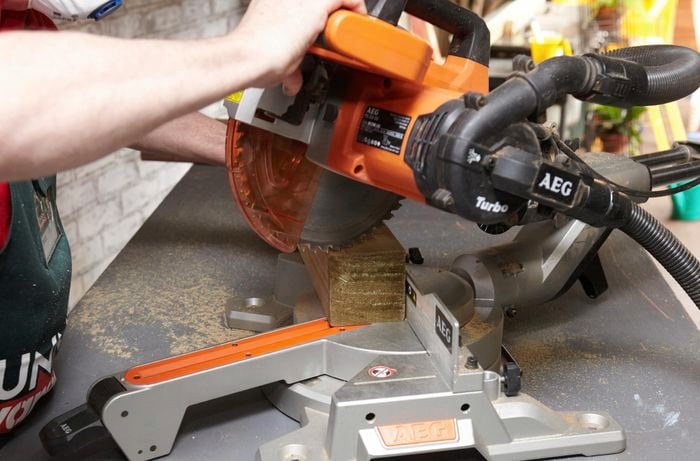 Person using circular saw to cut piece of timber.