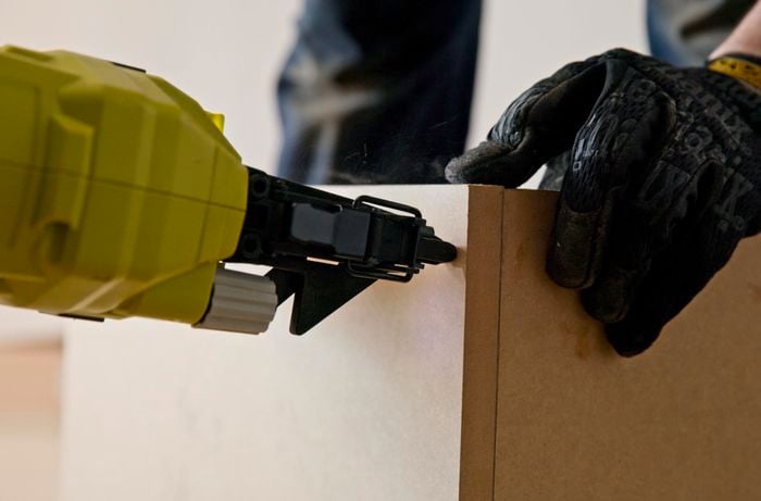 A person assembling the kickboards using a nail gun.