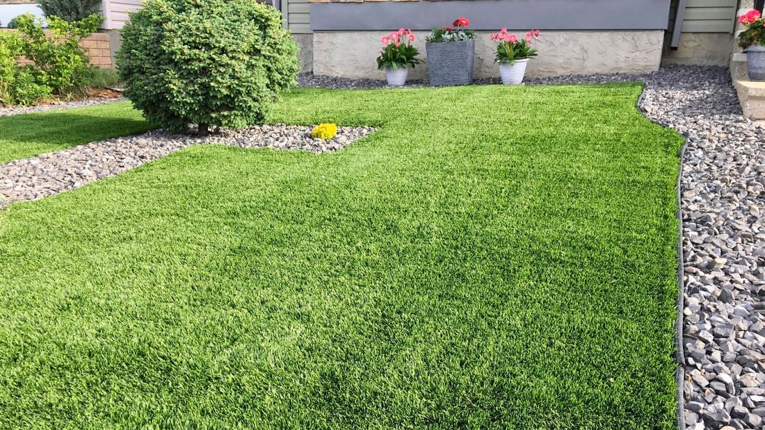 Image of a green lawn that meets a stone garden bed