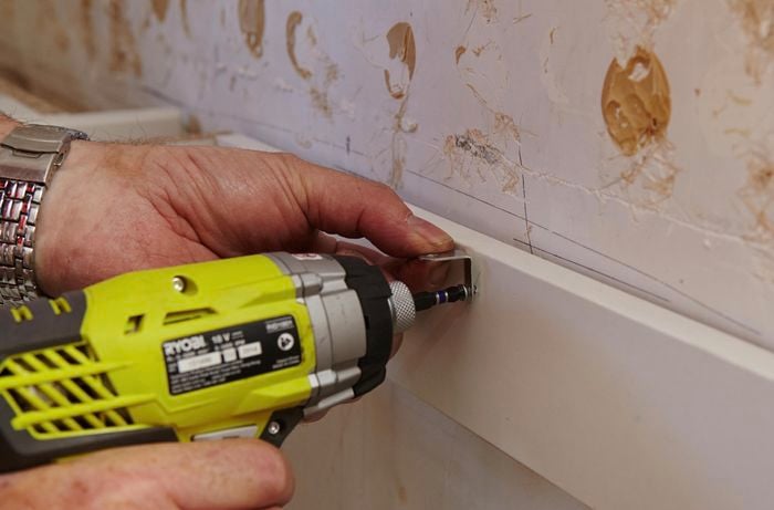 A piece of wood being drilled into a wall