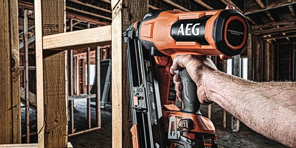 Close up of a man using a nail gun to secure timber framing