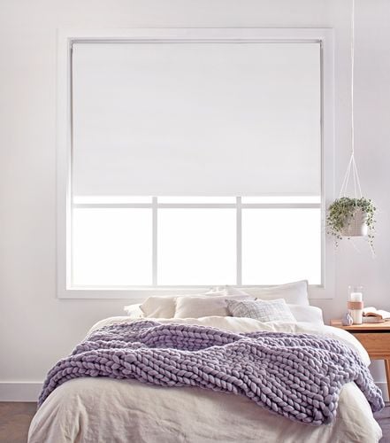 White painted bedroom with double bed and white roller blind half closed 