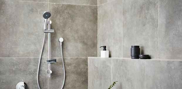 Chrome showerhead in focus in bathroom 