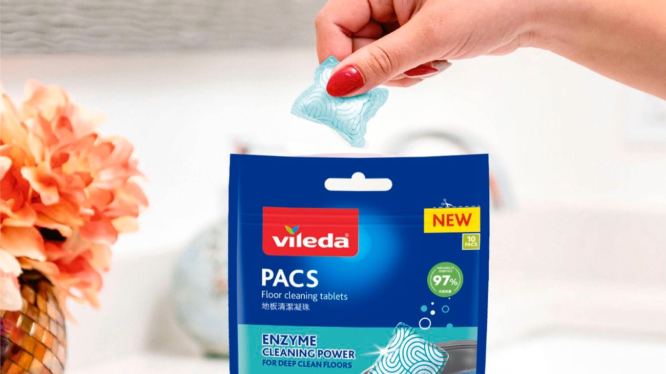 A woman's hand takes a PACS floor cleaning tablet out of the packet