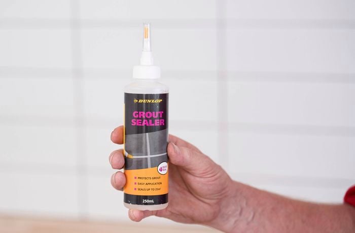 A person is holding a bottle of grout sealer 