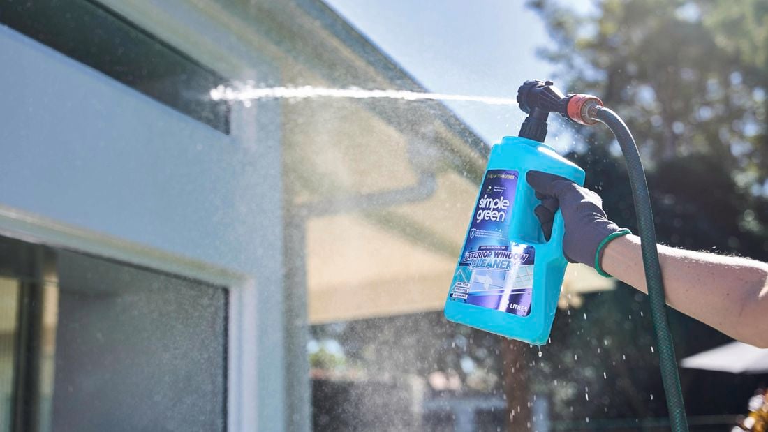 Blue Simple Green exterior window cleaner being sprayed by a gloved hand
