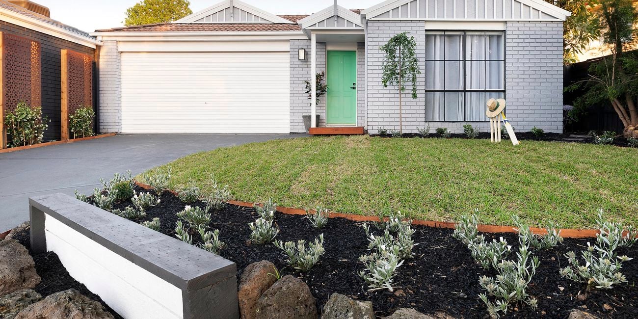 Newly painted house, with freshly laid turf and planted garden beds.