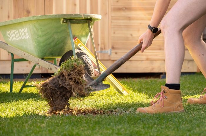 A person digging a hole in lawn