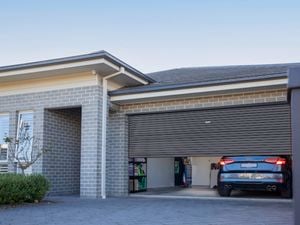 Modern brick house with black roller door and car in garage.