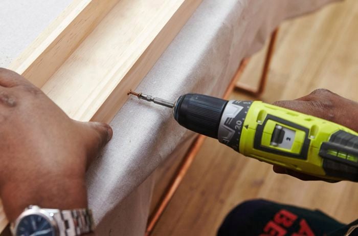 A person screwing into lengths of pine timber using a cordless drill