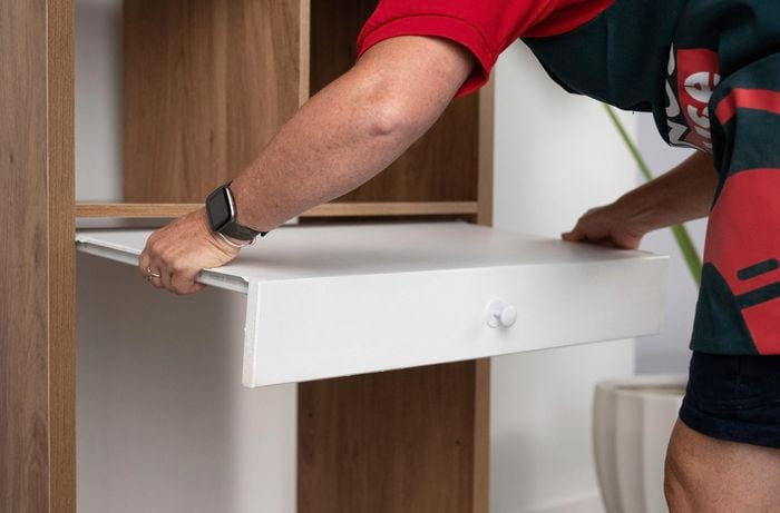 A Bunnings Team Member holding a shelve in front a shelving unit