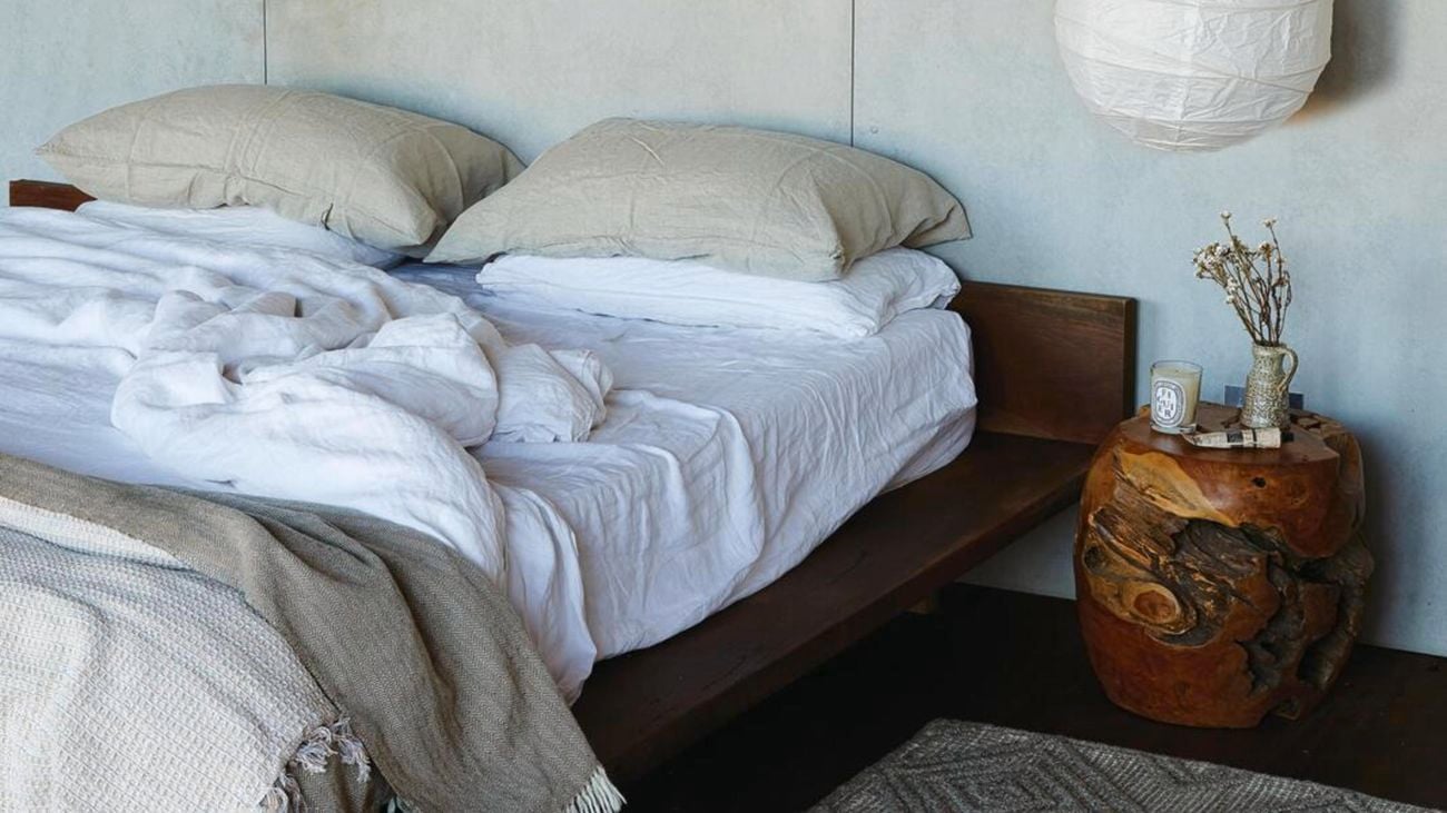 Mattress on wooden bed base with rug and side table