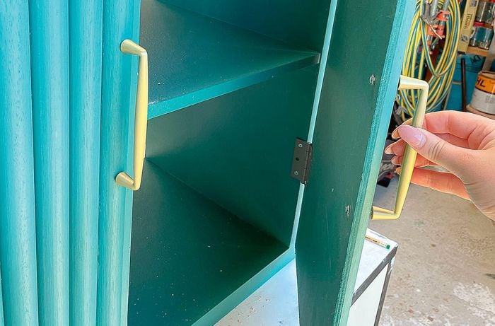 Painted dowel unit with one door opened by handle