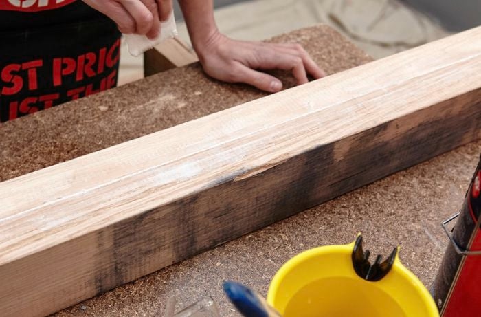 A Bunnings team member sanding down the upright of a wooden coat rack