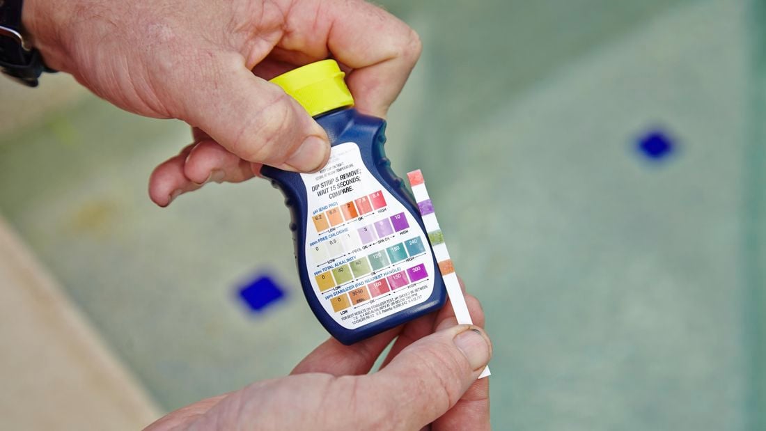 A pool test kit being used to measure the pH level, chlorine level, alkalinity and stabiliser