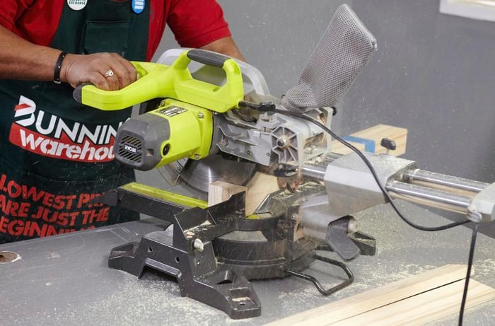 A person cutting pine timber with a drop saw