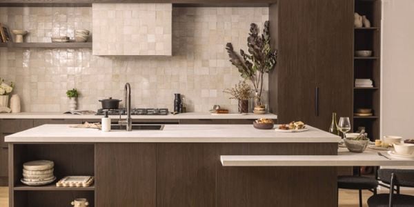 Modern chocolate brown kitchen with a marble benchtop and a tiled splashback behind the stove top.