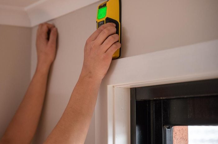 Using a stud finder on a wall