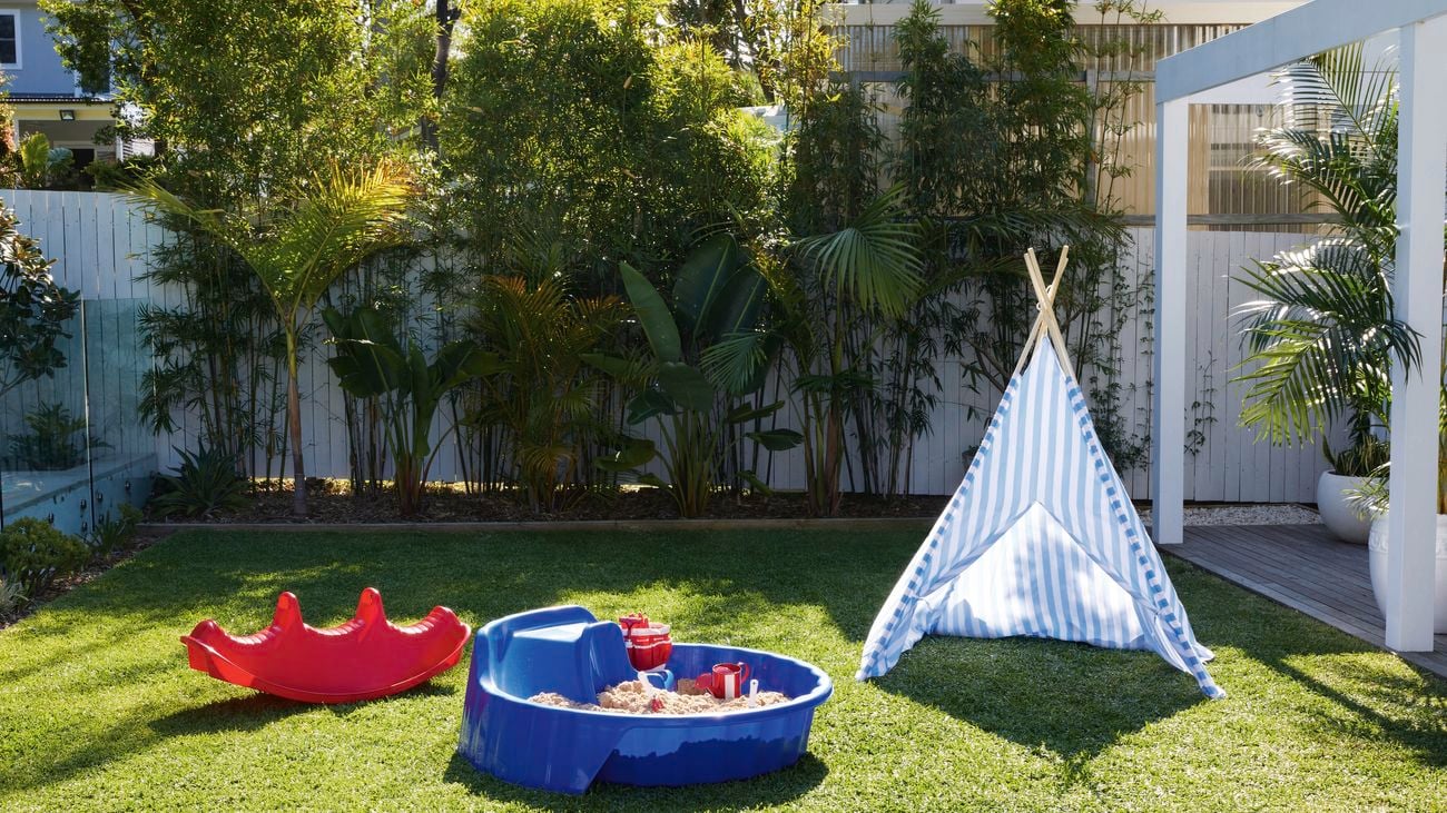 A kids tent and plastic toys set up on a grassy area to make a kids' play zone.