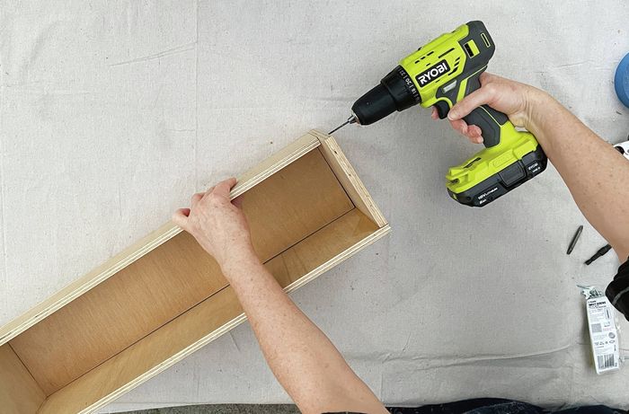 Hands using a drill to drill into a wooden box. [[2609] MAK...me sign_V1 | Word]