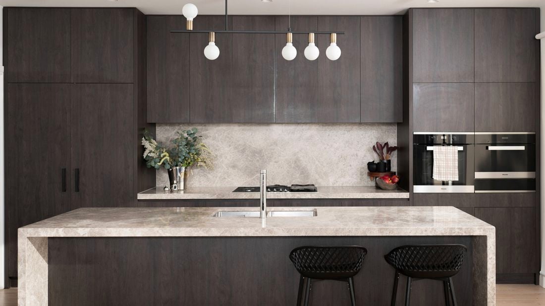 An image of a clean and organised kitchen featuring plenty of storage and a beautiful pendant light.