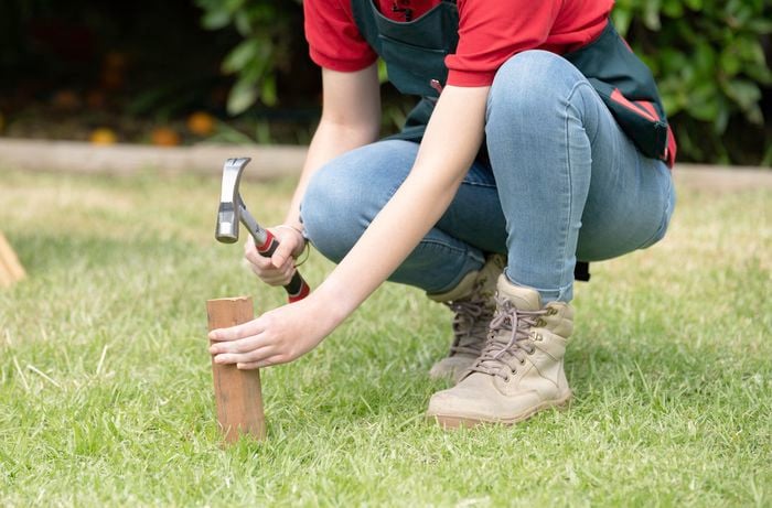 Hammering a garden stake into the ground.