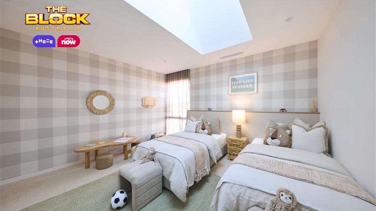 Sage and white bedroom with check wallpaper, two twin beds with white linen and a table and mirror on the wall.