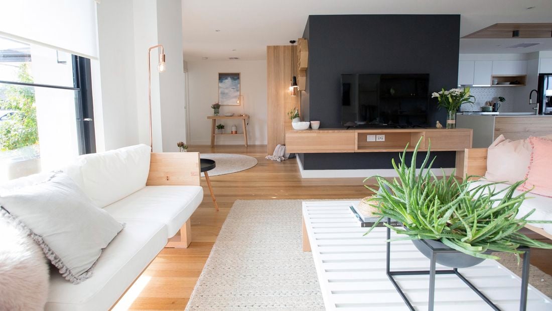 A modern open-plan kitchen and living area with timber floors and pale coloured furnishings 