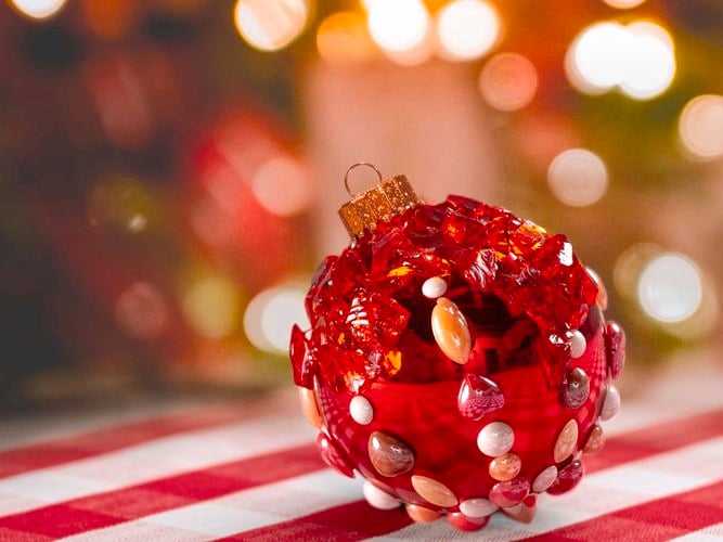 Bright red Christmas bauble with mosaic details set against a festive background. 