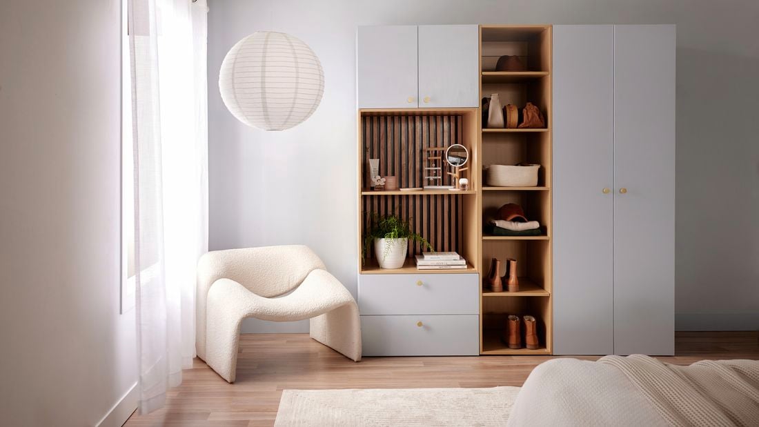 White storage cabinet in a bedroom with a white chair and a bed in it.