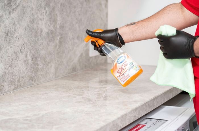 Person cleaning around a bathroom benchtop before silicone removal