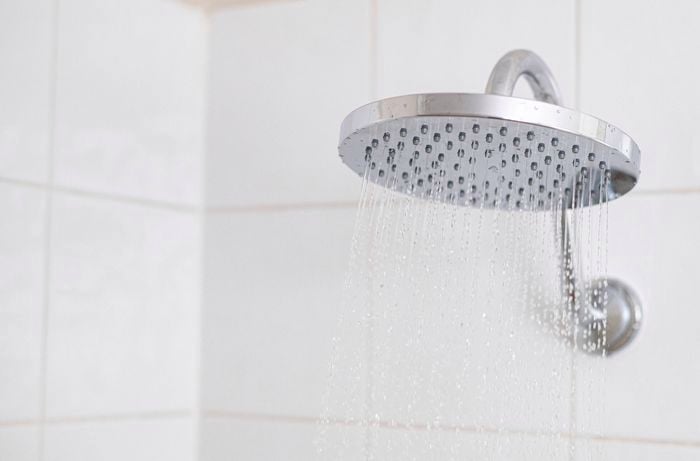 A shower head with water flowing from it.