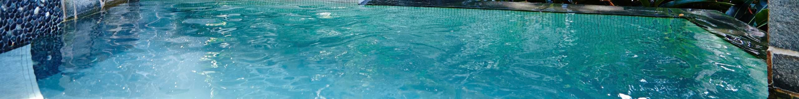 Timber lounge seat under a market umbrella on a pool deck