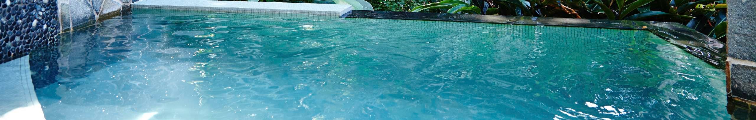 Timber lounge seat under a market umbrella on a pool deck