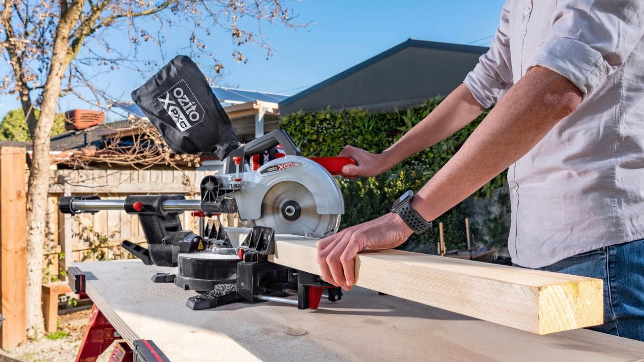 Person chopping block of wood with Ozito table saw.