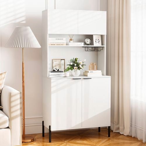 Storage cupboard with books, a clock, vase with flowers in it on it, sitting on a timber flooring with a standing lamp next to it.