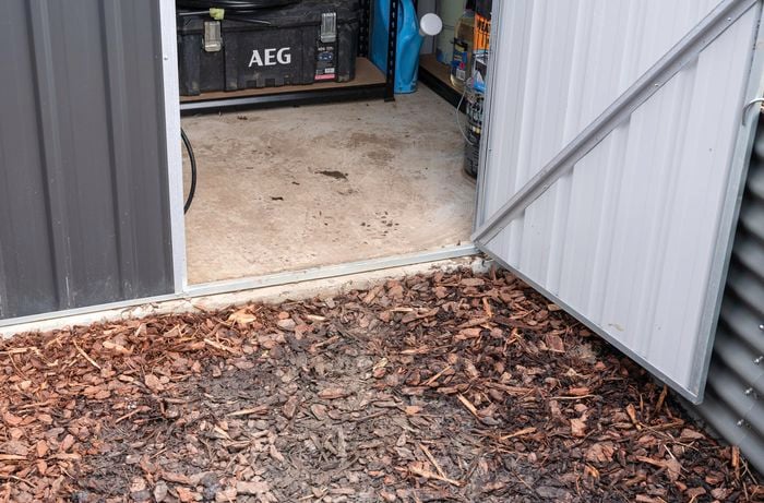 Open shed door with shed on concrete base.