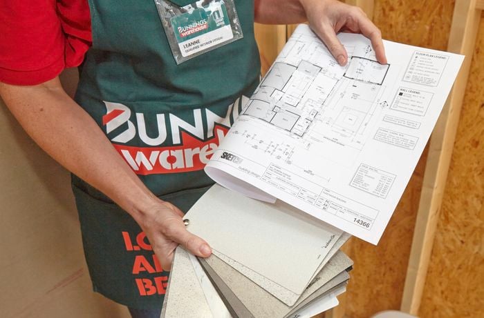 A person holding a house floor plan and laminate swatches
