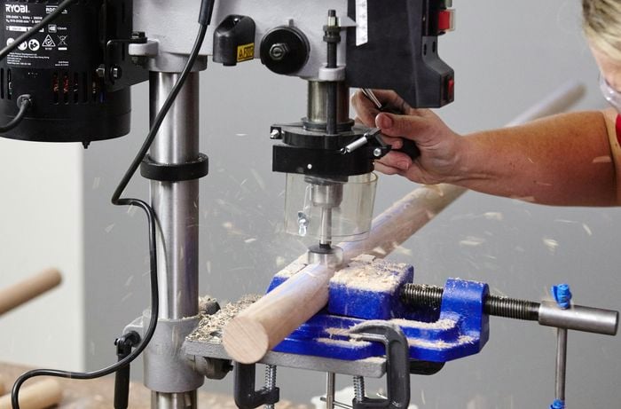 Person drilling holes in timber using wide drill bit.
