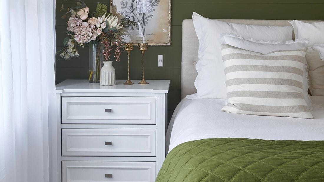 Organized and clean bedroom with bed, side table and decoration. 