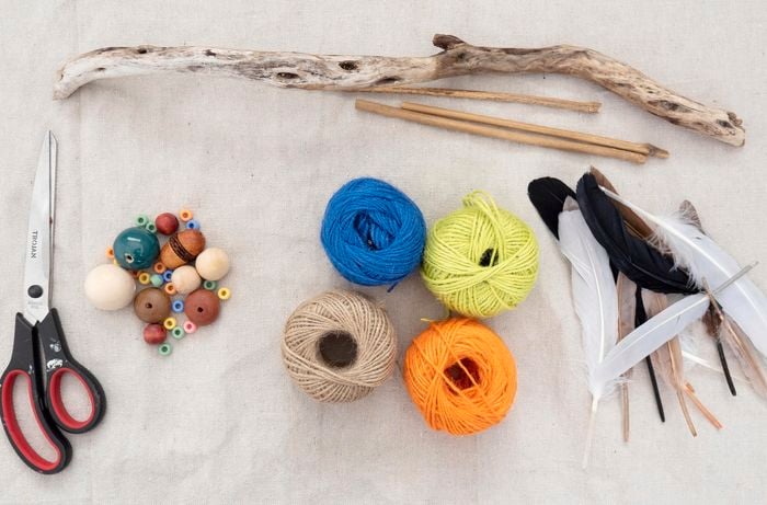 A flat lay with scissors, sticks, feathers, string and beds